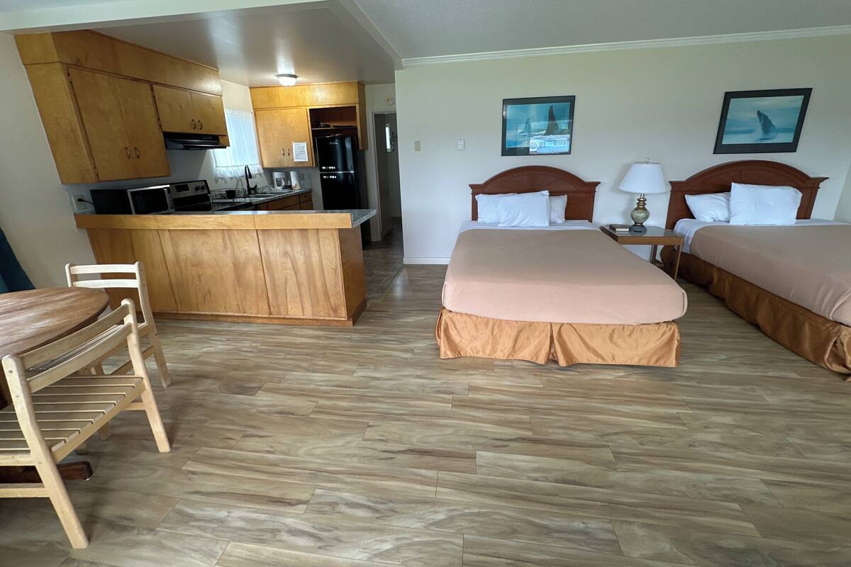 A hotel room with two beds, a kitchenette, and a dining area.