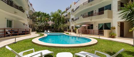 Una piscina al aire libre, sillones reclinables de piscina