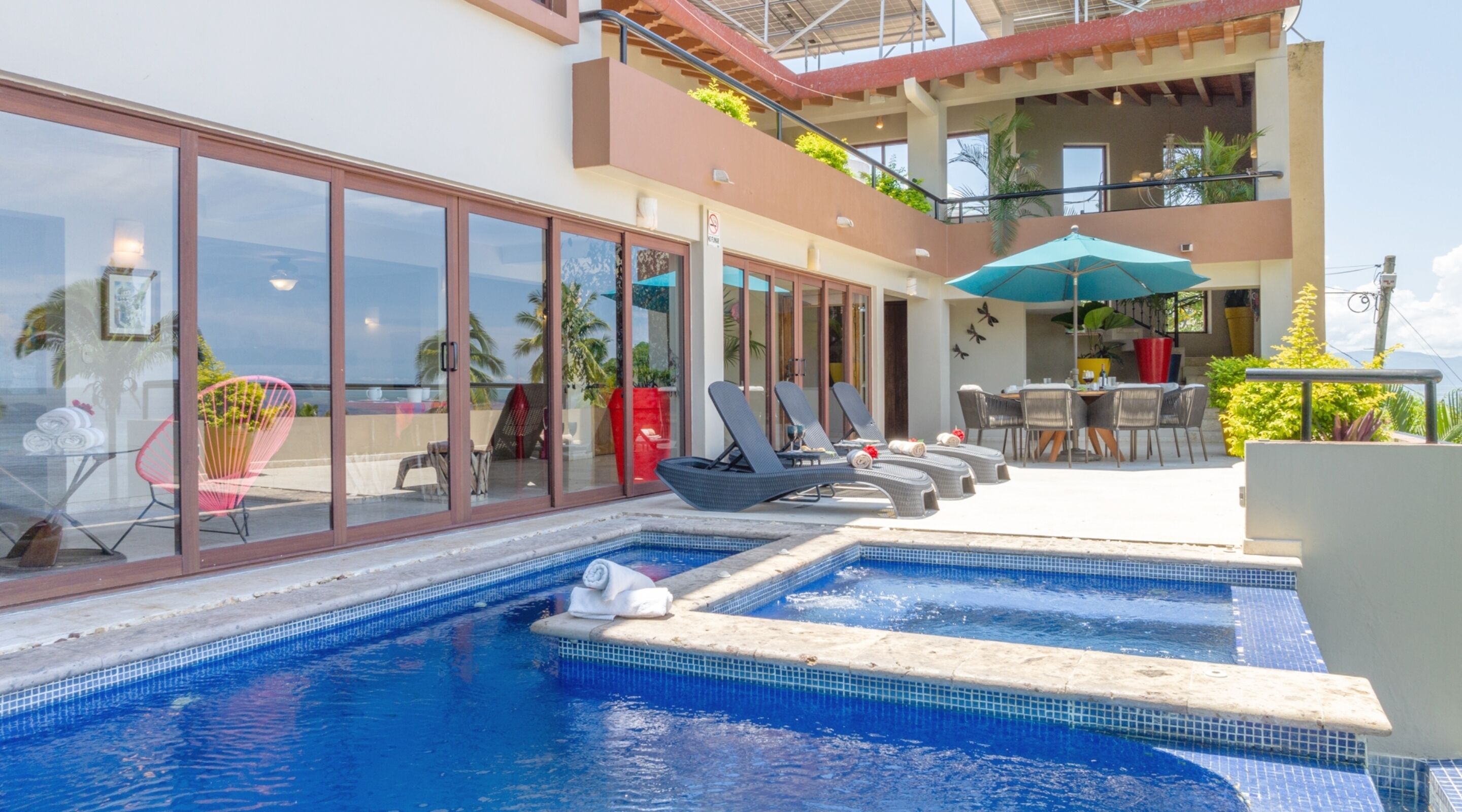 A swimming pool with lounge chairs and a dining area.