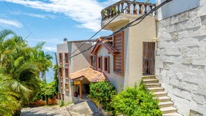 A two-story building with a balcony, a tiled roof, and a staircase leading to the entrance. - Casa Bahia Linda by Kivoya (Puerto Vallarta)