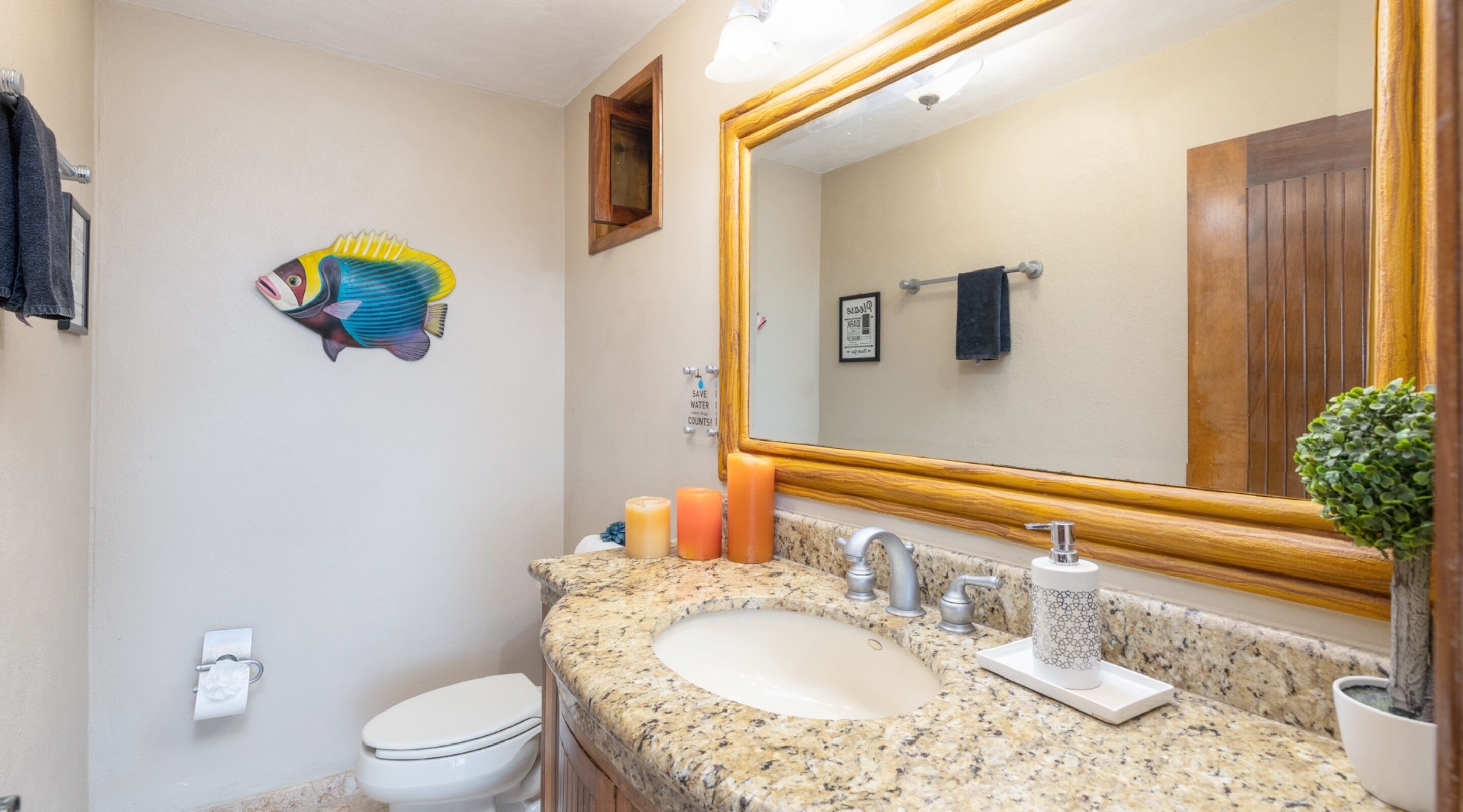 A bathroom with a granite countertop, a sink, a mirror, and a toilet.