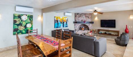 A spacious living area with a dining table, sofa, and fireplace.