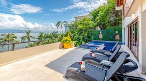 A balcony with a pool, lounge chairs, and a view of the ocean. - Casa Bahia Linda by Kivoya (Puerto Vallarta)