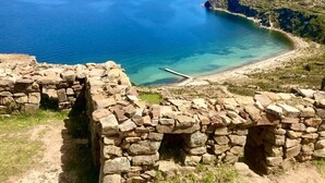 A stone structure with a view of a calm sea and distant mountains. - Hotel Wendy Mar (Copacabana)