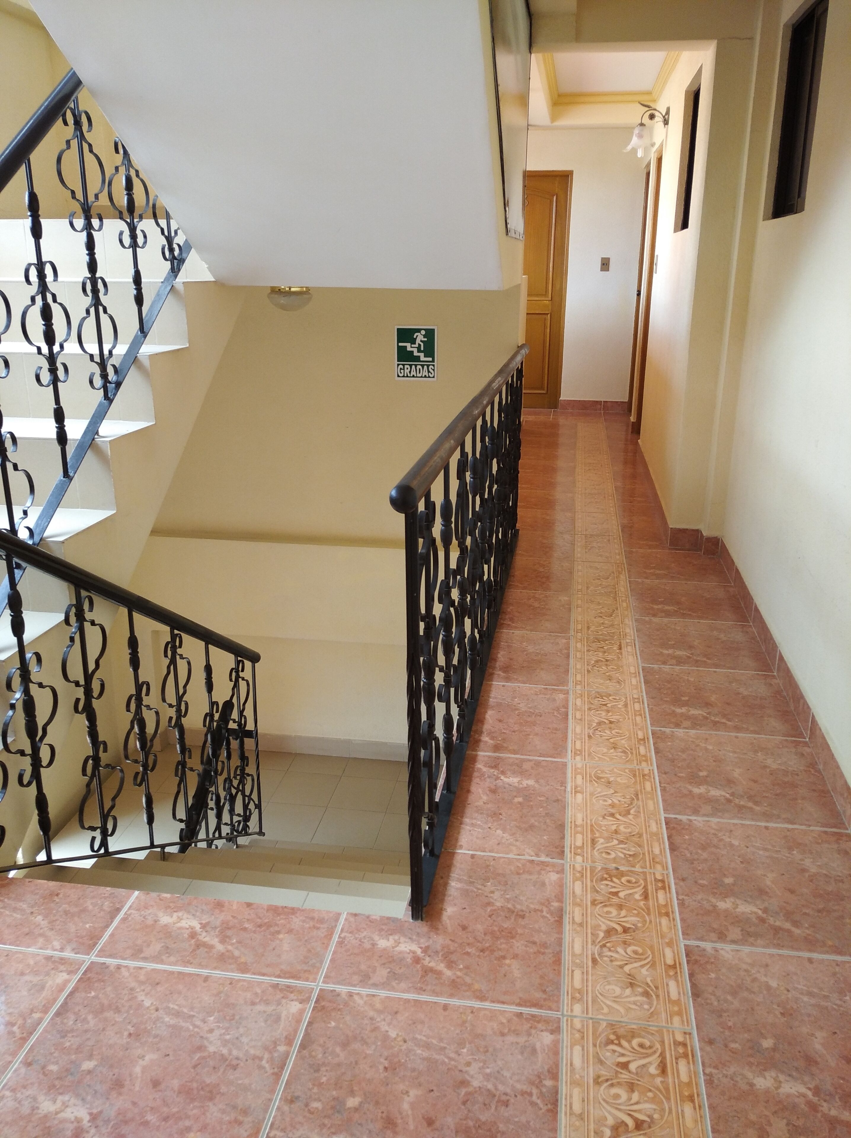 A staircase with ornate black railings, a sign indicating a handicap-accessible area, and a patterned floor.