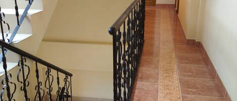 Una escalera con barandillas negras ornamentadas, un letrero que indica una zona accesible para personas con discapacidad y un suelo con diseño.