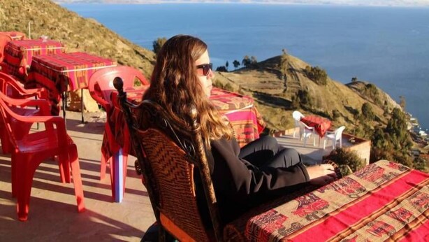 A person seated on a chair with a view of a body of water and hills in the background. - Hotel Wendy Mar (Copacabana)