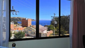 A window with a clear view of a coastal town, buildings, and a body of water. - Hotel Wendy Mar (Copacabana)