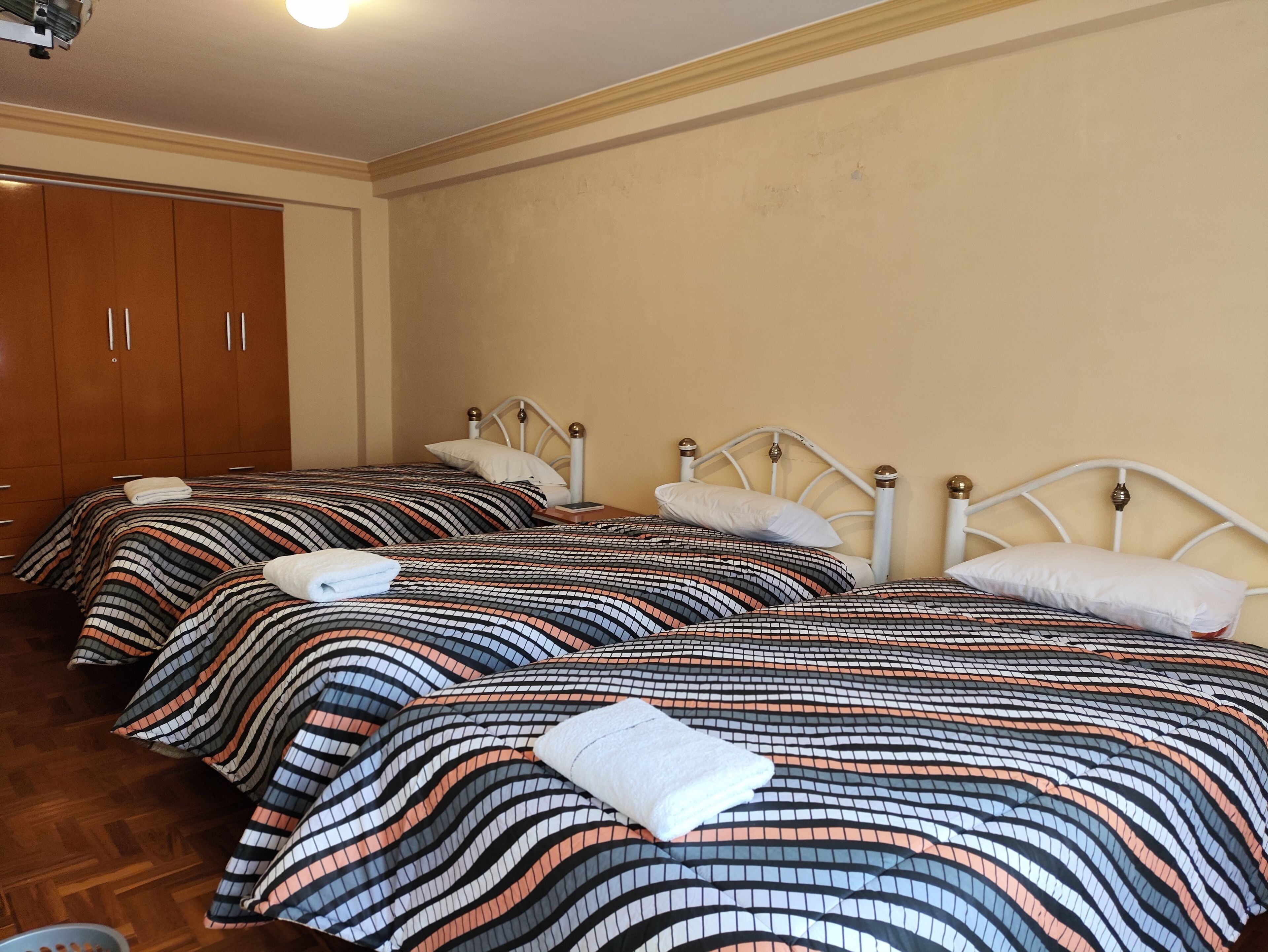 Habitación de hotel con dos camas, armario de madera y una lámpara en el techo.