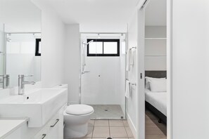 A modern bathroom with a shower, toilet, and sink.