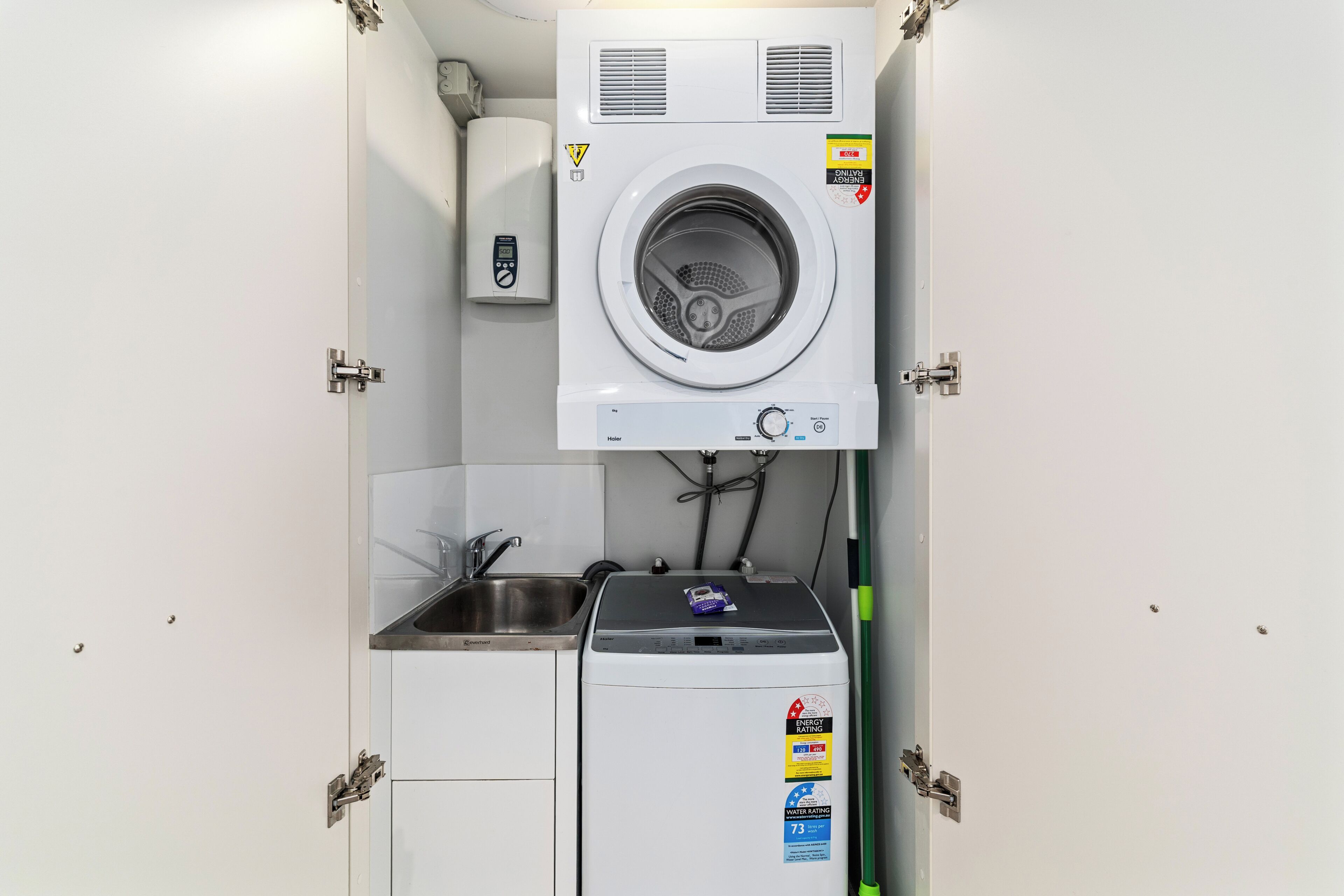A compact laundry room with a washing machine, a dryer, and a small sink.