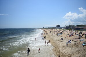 Une plage où l’on voit des gens se promener le long du rivage et d’autres se détendre sur le sable.