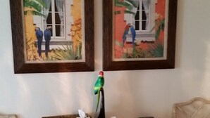 Una habitación con una consola blanca, una pequeña estantería y dos cuadros enmarcados de pájaros en una pared.