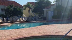 Una piscina con solárium y sillas de descanso.