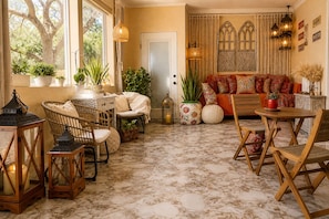 A cozy living room with a sofa, chairs, a table, and potted plants.