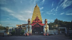 A temple with a tall, golden spire and two lion statues at the entrance.