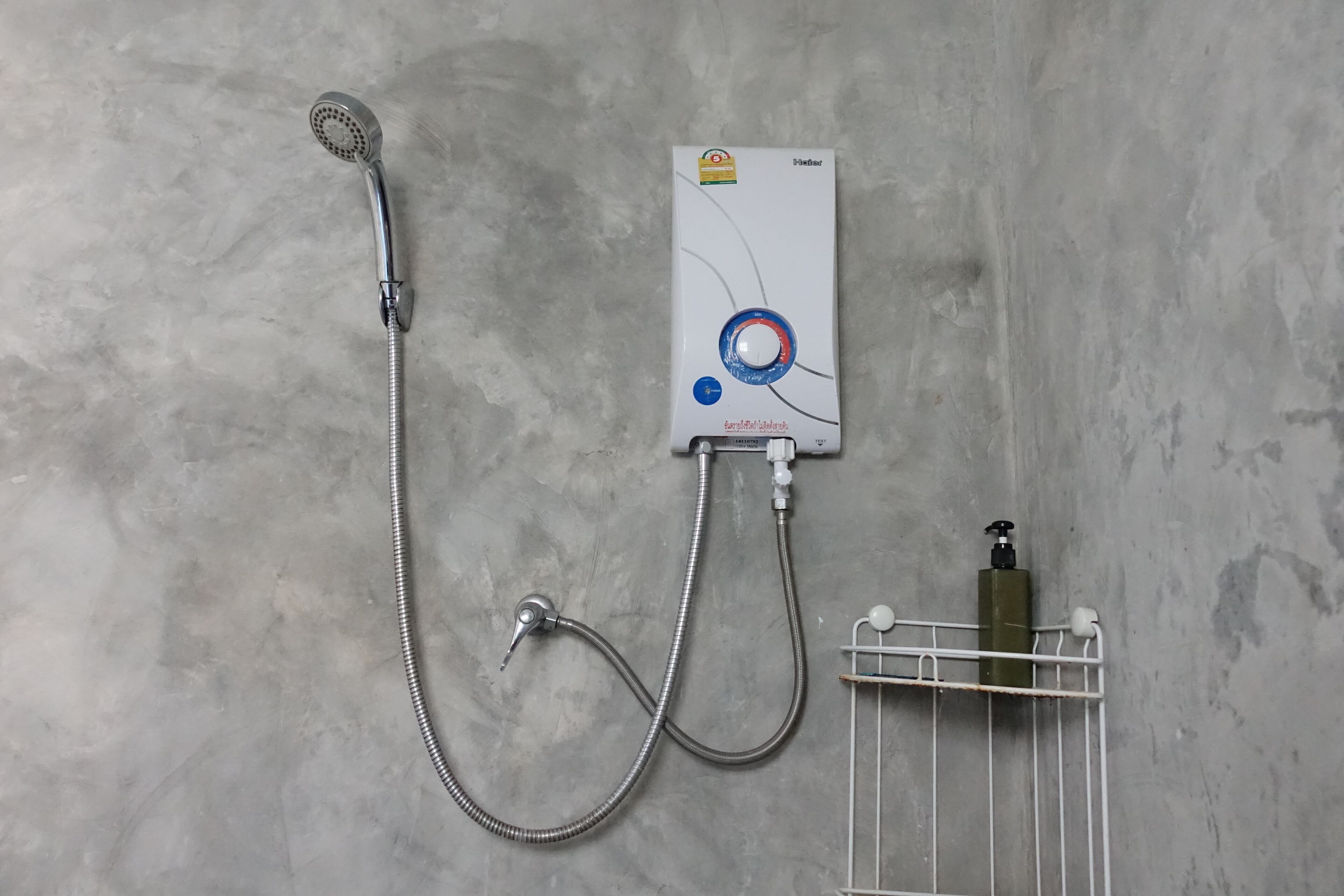 A wall-mounted shower unit with a handheld showerhead and a control panel.