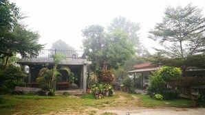A covered outdoor area with a concrete structure, surrounded by greenery and trees.