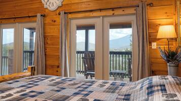 Une chambre dans un chalet en bois, avec un lit, une horloge et un balcon équipé d’une chaise.