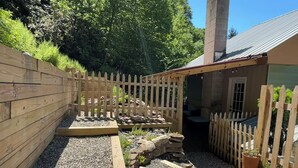 A wooden deck with a stone pathway, a small wooden shed, and a metal roof structure. - Spacious 3 Bedroom, 2 Bath Apartment-historic Jim Thorpe, large patio & balcony (Jim Thorpe)