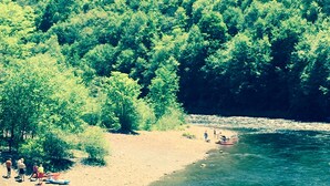 A riverbank with people and kayaks, surrounded by dense green forest. - Spacious 3 Bedroom, 2 Bath Apartment-historic Jim Thorpe, large patio & balcony (Jim Thorpe)