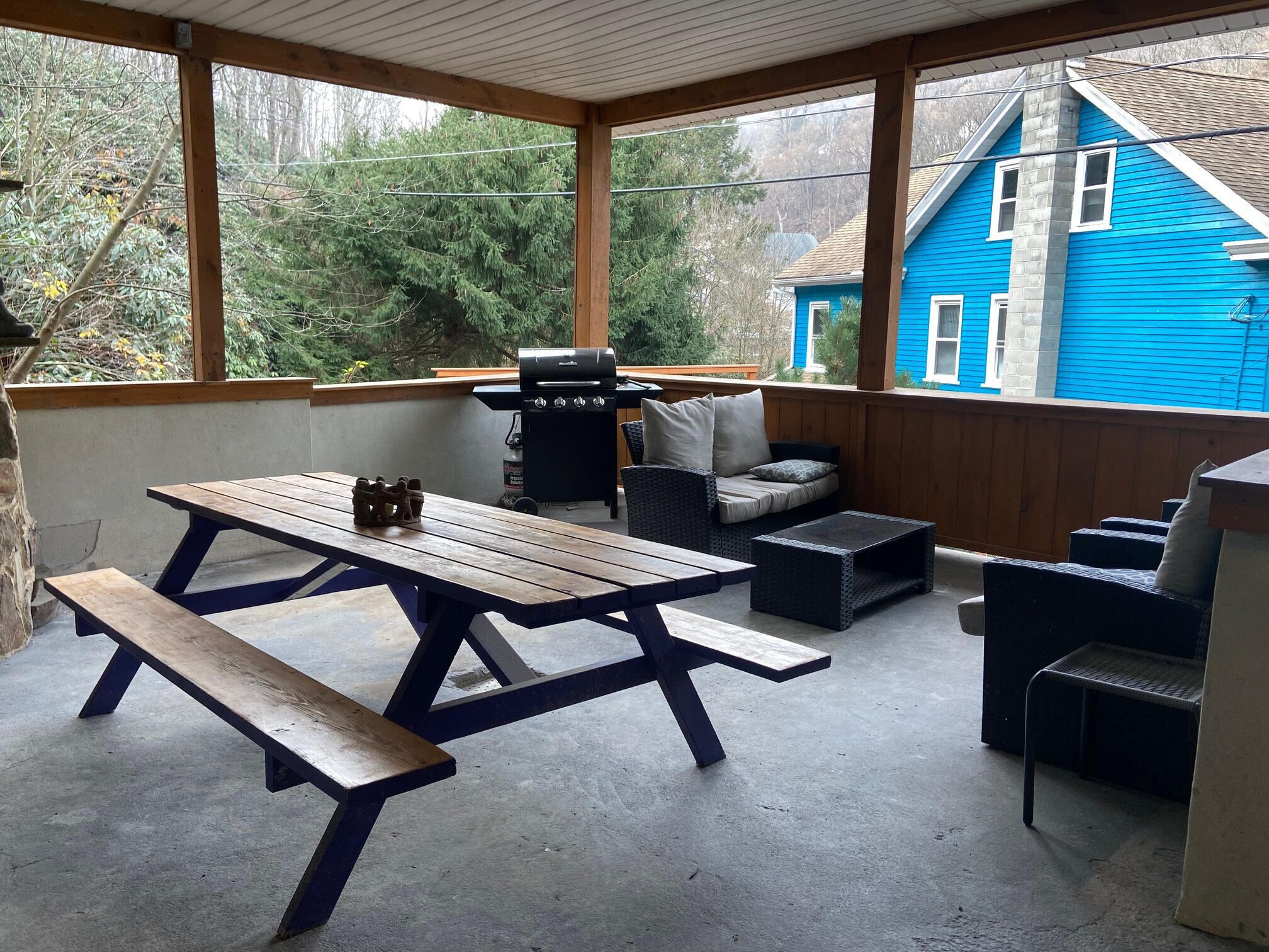 A covered patio with a picnic table, outdoor seating, and a grill.