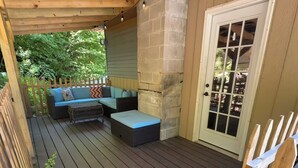 A covered outdoor deck with a wooden bench, a cushioned seating area, and a door with glass panels. - Spacious 3 Bedroom, 2 Bath Apartment-historic Jim Thorpe, large patio & balcony (Jim Thorpe)