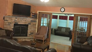 A living room with a stone fireplace, leather sofas, a television, and a ceiling fan. - 6 BDRM BEAUTIFUL HOME ON ONE FLOOR "LIONS DEN" -Big Boulder,Camelback,Jack Frost (Lake Harmony)