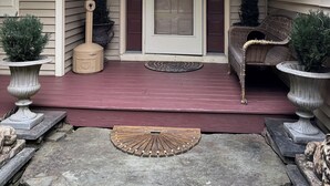 A covered porch with a door, two potted plants, a wicker chair, and a stone bench. - 6 BDRM BEAUTIFUL HOME ON ONE FLOOR "LIONS DEN" -Big Boulder,Camelback,Jack Frost (Lake Harmony)