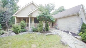 A two-story house with a front porch, a stone pathway, and a well-maintained lawn. - 6 BDRM BEAUTIFUL HOME ON ONE FLOOR "LIONS DEN" -Big Boulder,Camelback,Jack Frost (Lake Harmony)