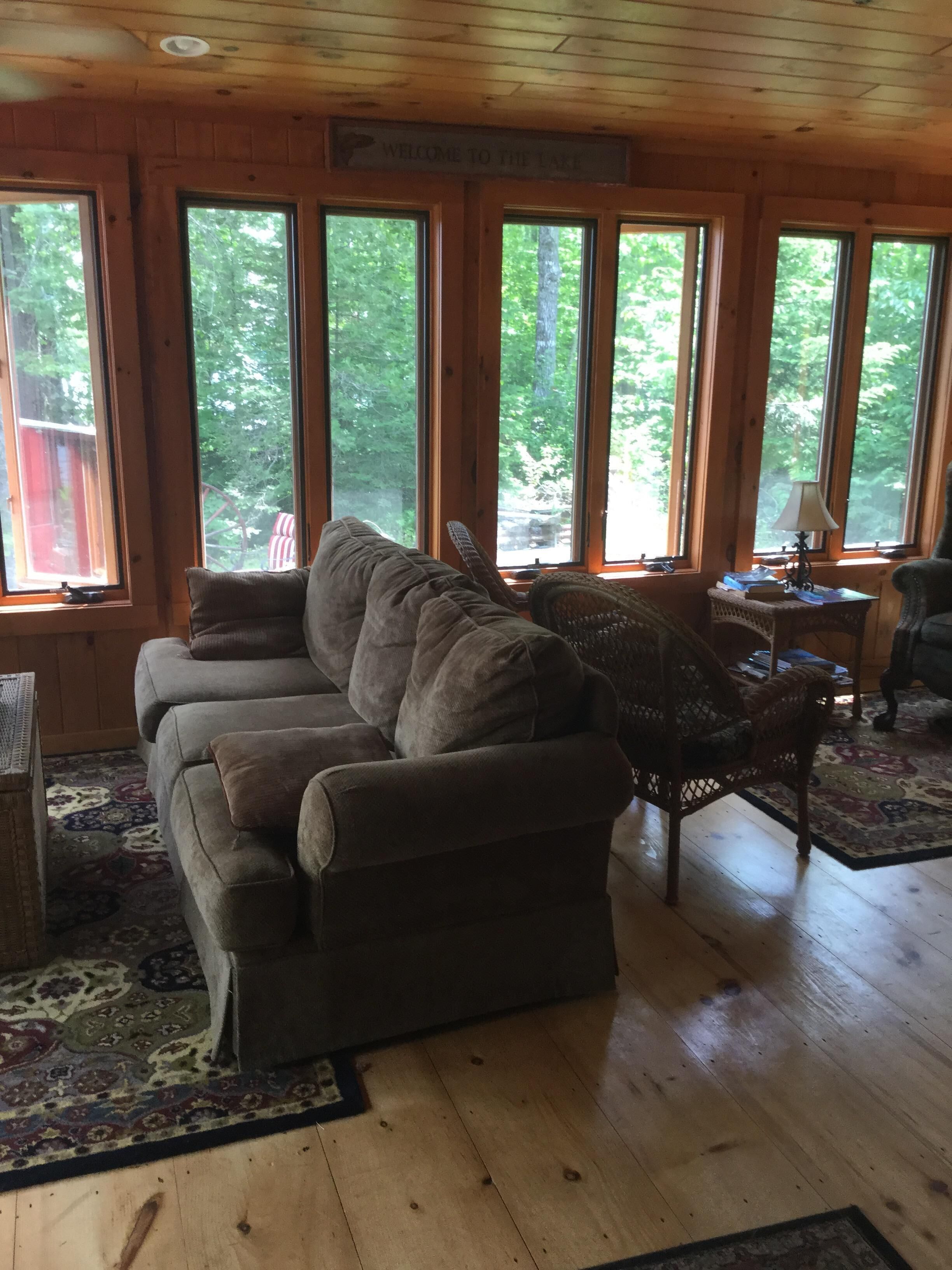 Un intérieur de chalet chaleureux avec un grand canapé, un fauteuil en osier et un tapis.