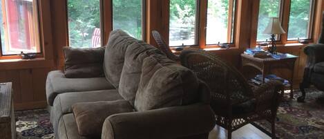 Un intérieur de chalet chaleureux avec un grand canapé, un fauteuil en osier et un tapis.