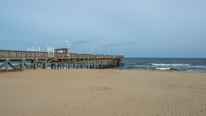 A wooden pier extending into the ocean with a sandy beach in the foreground. - Breathtaking Sunsets On Back Bay- Your Sandbridge Escape Awaits! (Virginia Beach)