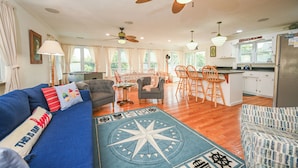 A spacious living area with a sofa, chairs, a dining table, and a kitchen area. - Breathtaking Sunsets On Back Bay- Your Sandbridge Escape Awaits! (Virginia Beach)