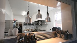 Une cuisine avec des luminaires suspendus, un comptoir avec des ustensiles et une pile d’assiettes.