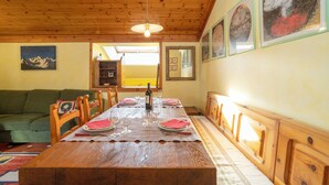 A dining area with a wooden table set for four, chairs, a wooden ceiling, and framed artwork on the walls. - BEAUTIFUL ATTIC ROOM WITH A VIEW OF THE SKI SLOPES (BORMIO)