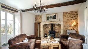 A rustic room with a stone fireplace, wooden furniture, and a chandelier. - BISE stylish 1600 SF wifi (Vitrac)