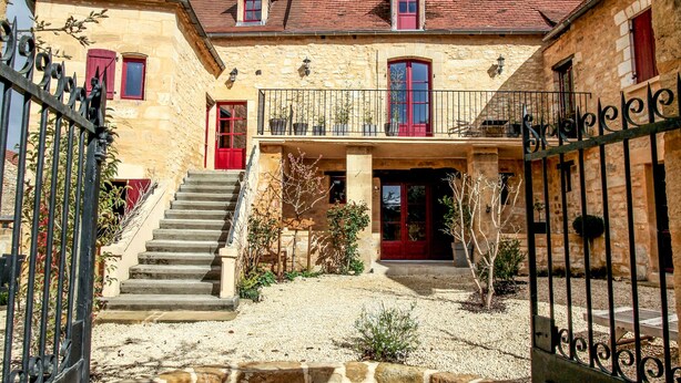 A stone building with a red door and a staircase leading to a balcony. - BISE stylish 1600 SF wifi (Vitrac)