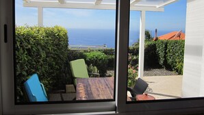 A patio with a view of the ocean, a wooden table, and two chairs. - CASA IVA 3 bedroom, 3 bathroom House with swimming pool and sea views (Estreito da Calheta)