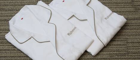 Two neatly folded white shirts with "Richmon" embroidered on them, placed on a textured carpet.