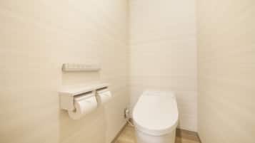 A small, modern bathroom with a toilet, a toilet paper holder, and a wall-mounted electrical outlet.