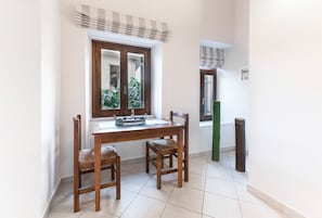 A dining area with a wooden table and chairs, a window with curtains, and a view of greenery outside.