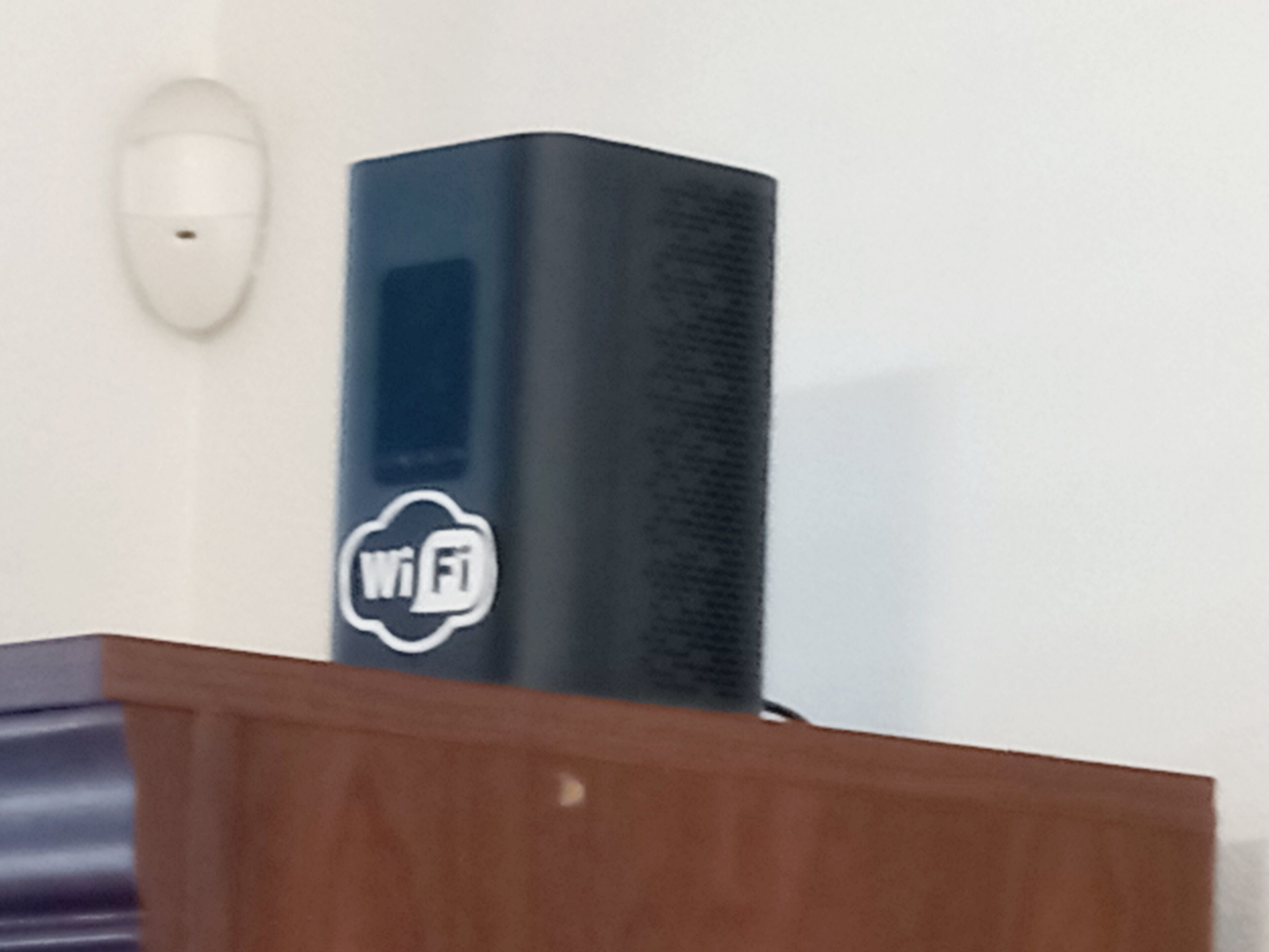 Um roteador WiFi preto sobre um armário de madeira.