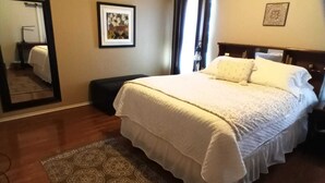 Un dormitorio con una cama grande, un ventilador de techo, una alfombra y un espejo.