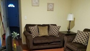 A living room with a brown sofa, a small table, a lamp, and a television. - The Carter's Wildwood Rentals- Suite #4 (Wildwood)