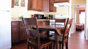 A kitchen with wooden cabinets, a dining table with chairs, a refrigerator, a microwave, and a coffee maker. - The Carter's Wildwood Rentals- Suite #4 (Wildwood)