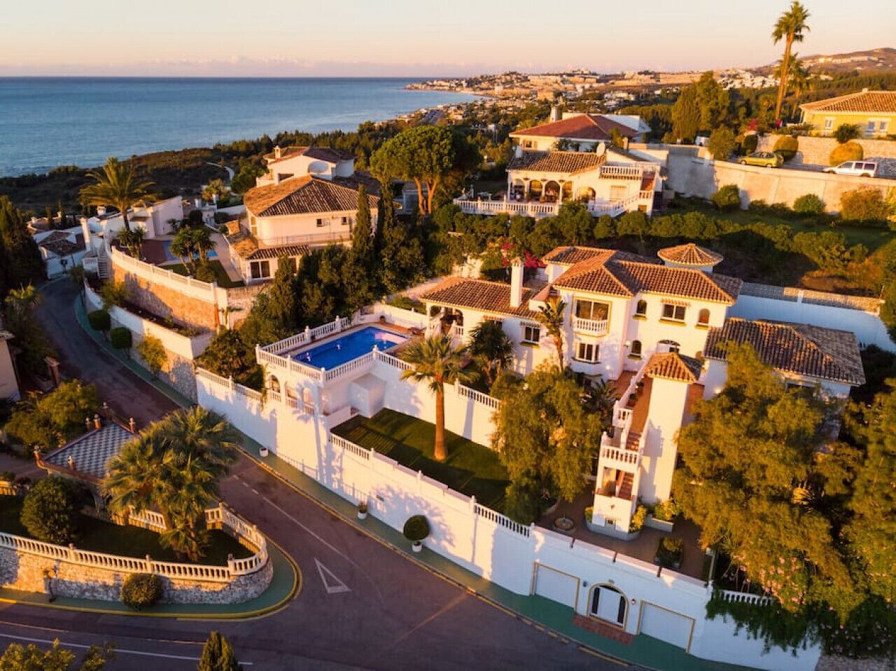 A coastal residential area with houses, a swimming pool, and a road.