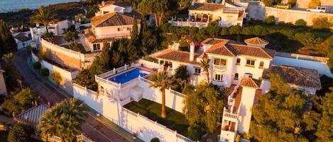 A coastal residential area with houses, a swimming pool, and a road.