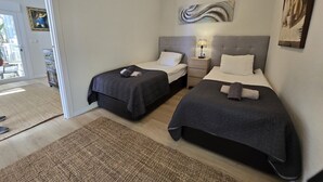 A hotel room with two beds, a nightstand, a lamp, and a painting on the wall.