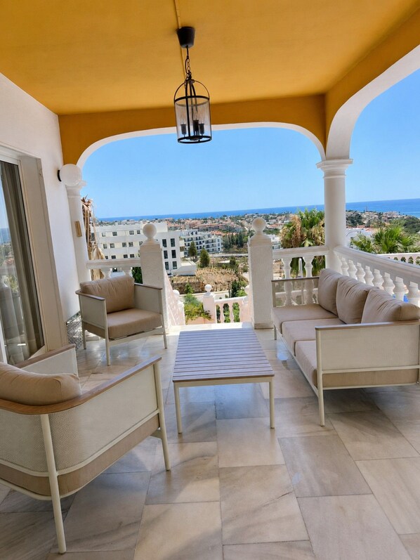 A balcony with a view of the sea, furnished with two sofas and a table.